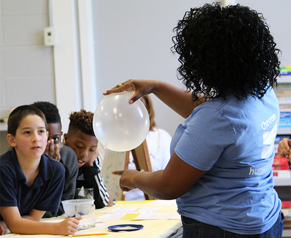volunteer holding a balloon demonstrating an experiment for students